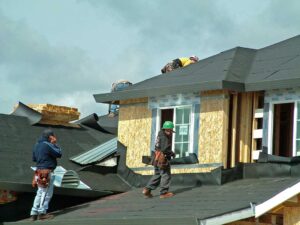 Homeowner examining roof shingles and gutters from the ground beside a residential house.